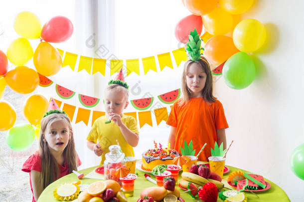 孩子们庆祝生日。孩子吹出蛋糕上的蜡烛。水果派对.