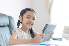 小亚洲女孩使用平板电脑和微笑与幸福为教育