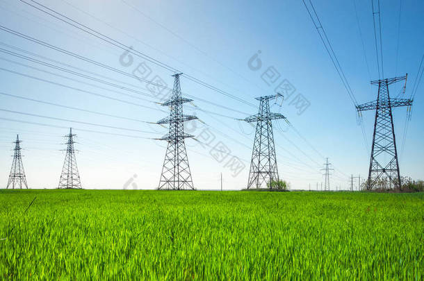 绿色农业景观中的高压线路和电力塔在晴天的蓝天下.