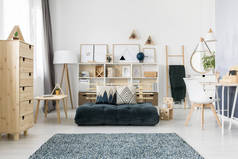 绿色折叠床垫和图案放置在斯堪的纳维亚客厅内部与木制家具和简单的画廊