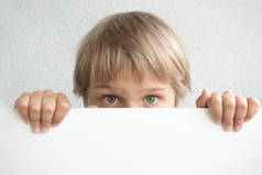 小男孩抱着空白的白色标志或标语牌遮住他的脸