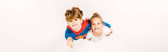 全景拍摄的快乐孩子在超级英雄服装拥抱朋友和手势上的白色 