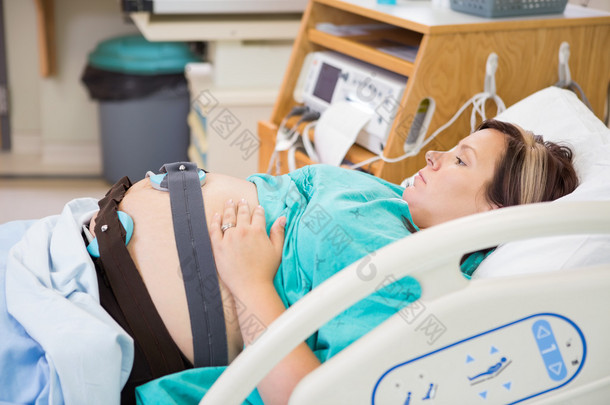 分娩的母亲带着电子胎儿监护的肚子
