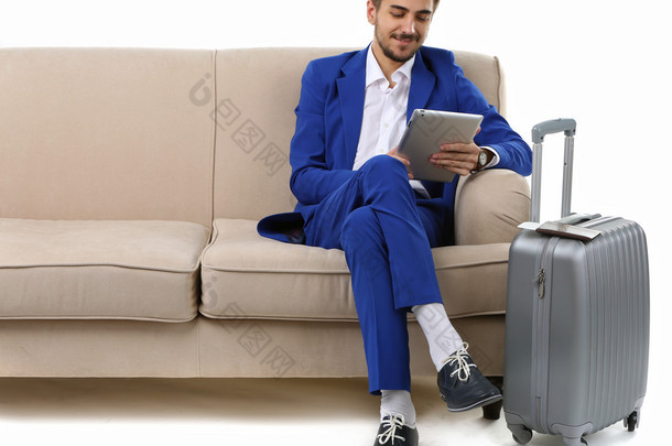 手提箱和平板电脑坐在沙发上白色孤立的业务人