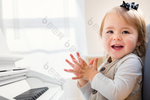 快乐的微笑蹒跚学步女孩<strong>兴奋</strong>地弹钢琴