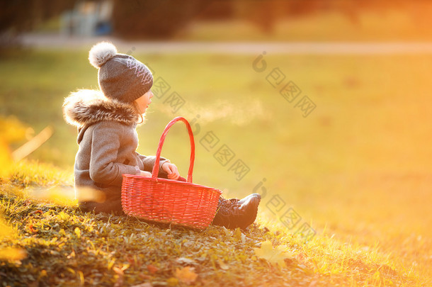 可爱的小女孩提着一个篮子在寒冷的秋日户外