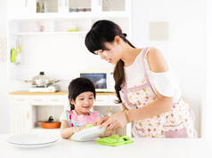 帮助她母亲干净盘子在厨房里的小女孩
