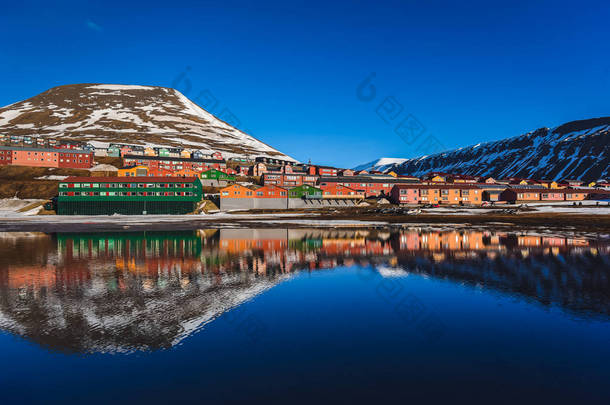 山水的北冰洋和反射与蓝蓝的天空和积雪，挪威斯匹次卑尔根，朗伊尔城，斯瓦尔巴德群岛的冬天山脉