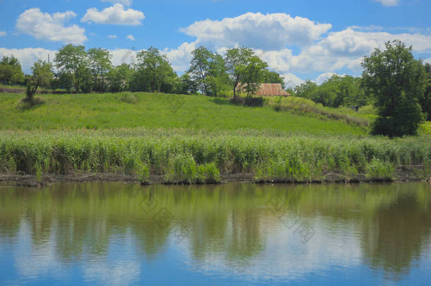 乡村景观的照片。绿色的山、 蓝色的湖和多云的天空，在炎热的夏天