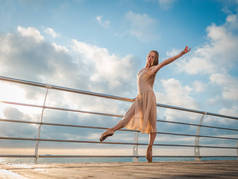 日出时在路基之上大洋或大海沙滩上跳舞芭蕾舞女演员在米色的丝绸衣服和普安特。年轻美丽的金发女子，长发练习与情感经典演习.
