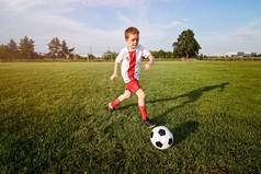 男孩玩足球球在运动场上.