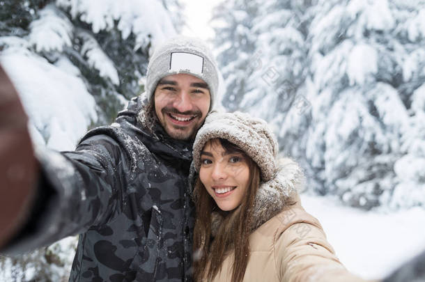 人采取自拍相片年轻浪漫夫妇微笑雪森林室外
