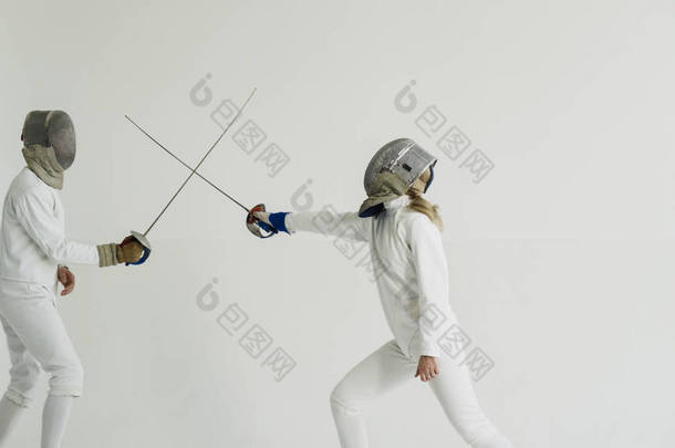 年轻女子击剑手击剑教练在白色演播室室内训练