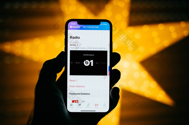 <strong>巴黎</strong>, 法国-2017年11月10日: 人拿着新的苹果 iphone X 10 显示与黄色星散<strong>背景</strong>以收音机音乐在 itunes 与敲打1