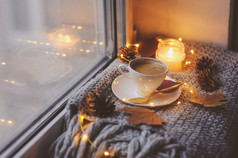 舒适的冬天或秋天的早晨在家。热咖啡用金金属勺, 暖毯, 花环和蜡烛灯, 瑞典 hygge 概念.