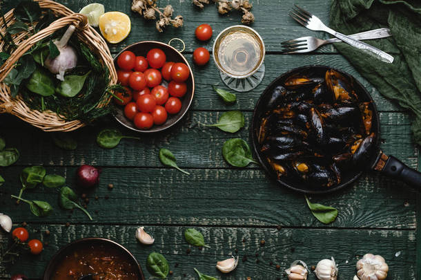 在乡间餐桌上用<strong>西红柿</strong>、香草和葡萄酒烹制的贝壳煮熟贻贝的美景