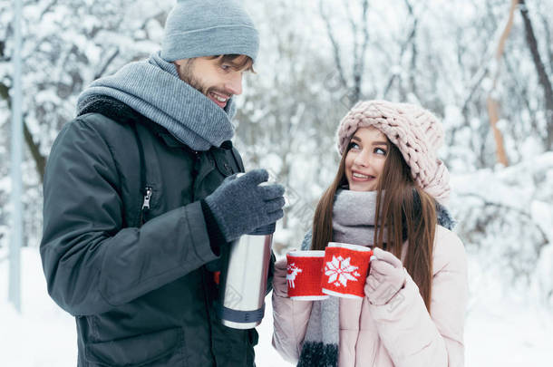 冬天公园里的小情侣在热水瓶里喝茶