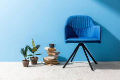 在蓝色墙壁前面与书和无花果罐的舒适的椅子