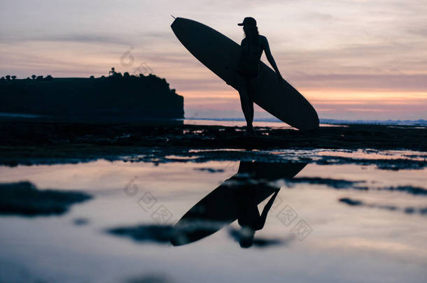 晚上海滨冲浪板的年轻女子剪影