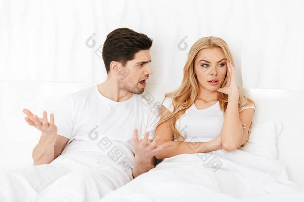愤怒的情侣躺在家里的床上吵架.