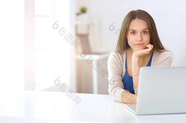 在书桌上使用膝上型电脑的美丽的<strong>年轻妇女</strong>