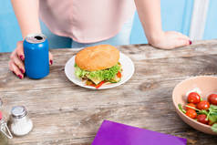 在桌上放着汉堡包, 超重的妇女用苏打饮料裁剪镜头