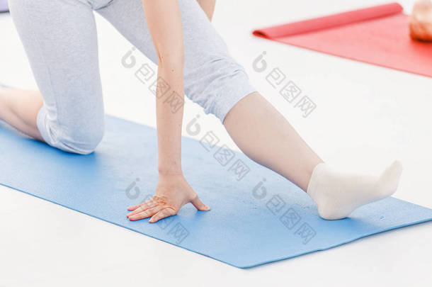 年轻的运动妇女在课堂上练习瑜伽, 做伸展运动。腿部和手特写细节视图