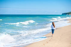 在阳光明媚的日子里沿着海边散步的小女孩，在海边健康休息