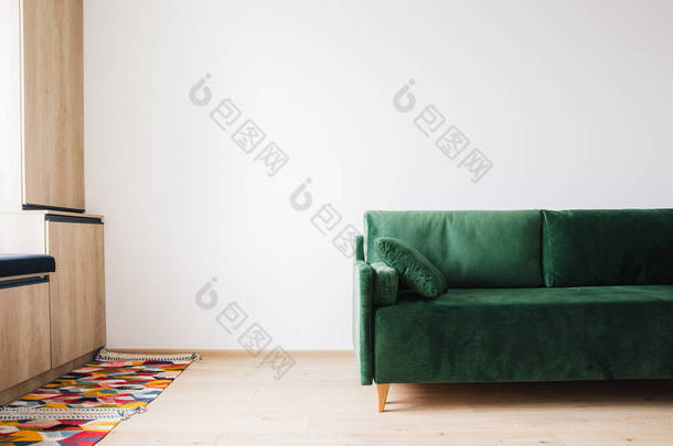绿色沙发，枕头近彩色地毯地板和木制橱柜