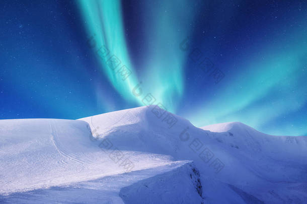 挪威洛福敦群岛上的北极光。山上绿色的北极光。夜晚的天空与极光。夜冬天风景与极光。挪威的自然背景