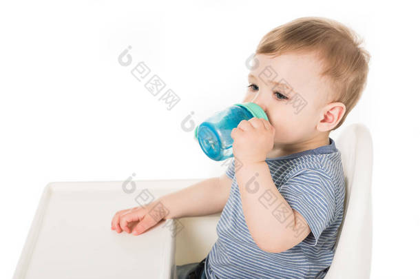  小男孩喝的<strong>水</strong>从<strong>婴儿</strong>杯和坐在高脚孤立的白色背景 