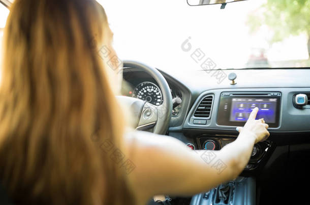 在驾驶汽车时使用触摸屏娱乐的年轻妇女的后方<strong>看法</strong>