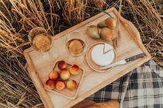 夏季户外娱乐活动。在麦田里野餐。Aperol，桃子，葡萄和奶酪顶部视图.