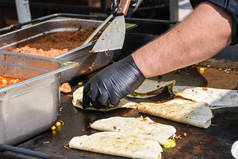 墨西哥传统菜肴- -墨西哥泡菜的制作过程。户外设置，厨师做饭期间的食品节，真正的街头食物。黑色手套味道鲜美。煮锅翻锅