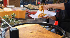 尼斯，法国，2020年2月25日：由Farinata或Cecina或Torta di ceci做成的大盘无酵薄煎饼或起自热那亚的鹰嘴豆面团在一个木制烤箱中烹调，出售