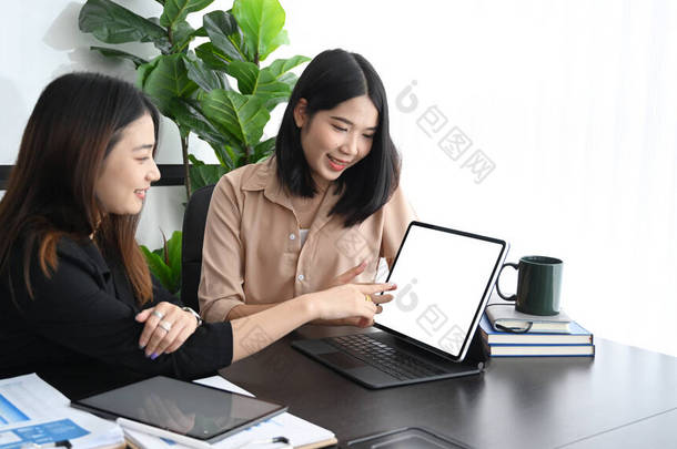 两名女商人使用平板电脑，在会议室讨论公司成长的策略.