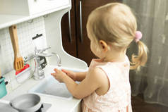 小女孩在儿童厨房用肥皂洗手。手部卫生规则概念,