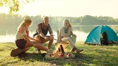 朋友们坐在 binfire 附近的夏季假期附近的湖边远足。背景露营
