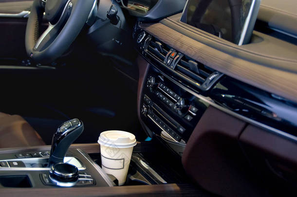 在汽车沙龙里喝咖啡。在汽车杯架内的一个纸咖啡杯.