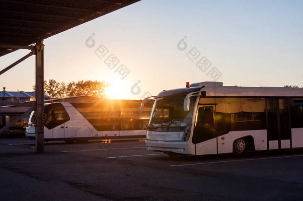 在夕阳的光线下在机场停车场穿梭巴士