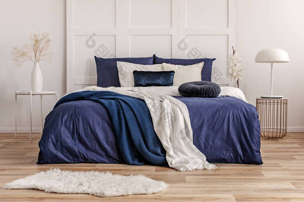 <strong>天鹅绒</strong>圆形枕头在特大号床与蓝色和白色床单