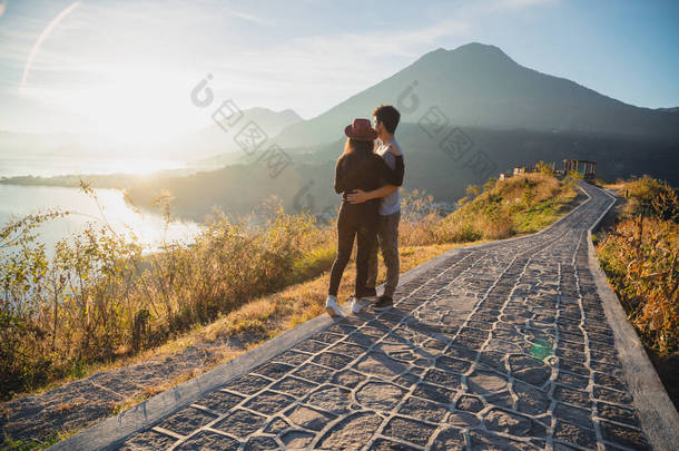 在圣胡安拉古纳湖观看日出的西班牙裔夫妇- -这对旅行中的夫妇拥抱在风景的顶端