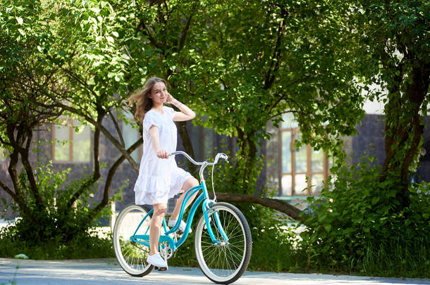 长头发的年轻妇女穿着自行车在公园里骑车