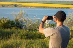 在帽子的农村男子欣赏日落的湖和黄土地