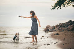 快乐的女人 2 0多岁时在海滩上散步时抱着她的狗的形象