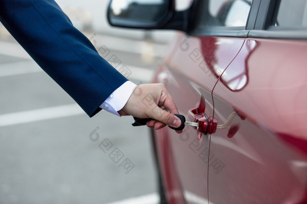 男子穿西装用钥匙打开车门的特写图片