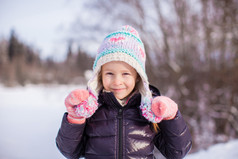 在冬天帽子在白雪皑皑的丛林中的小可爱女孩的画像