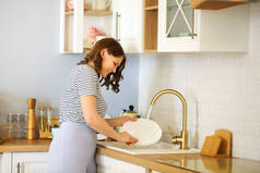 家庭主妇在家里厨房做家务活时洗碗的侧视图