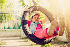 快乐的小女孩在绿色花园的轮胎摆动摆动 