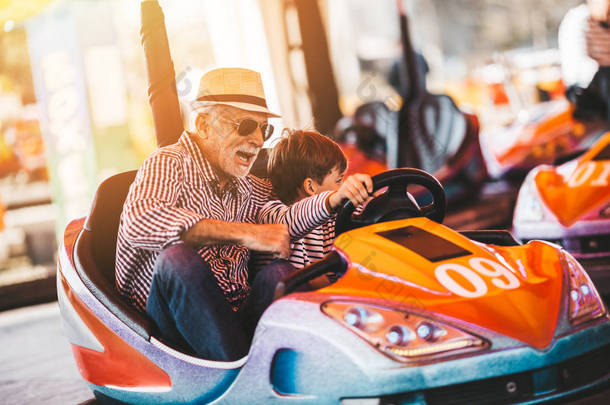 爷爷和孙子在<strong>游乐</strong>园里玩得很开心, 在一起度过了美好的时光。他们一边开保险杠车一边享受着微笑.